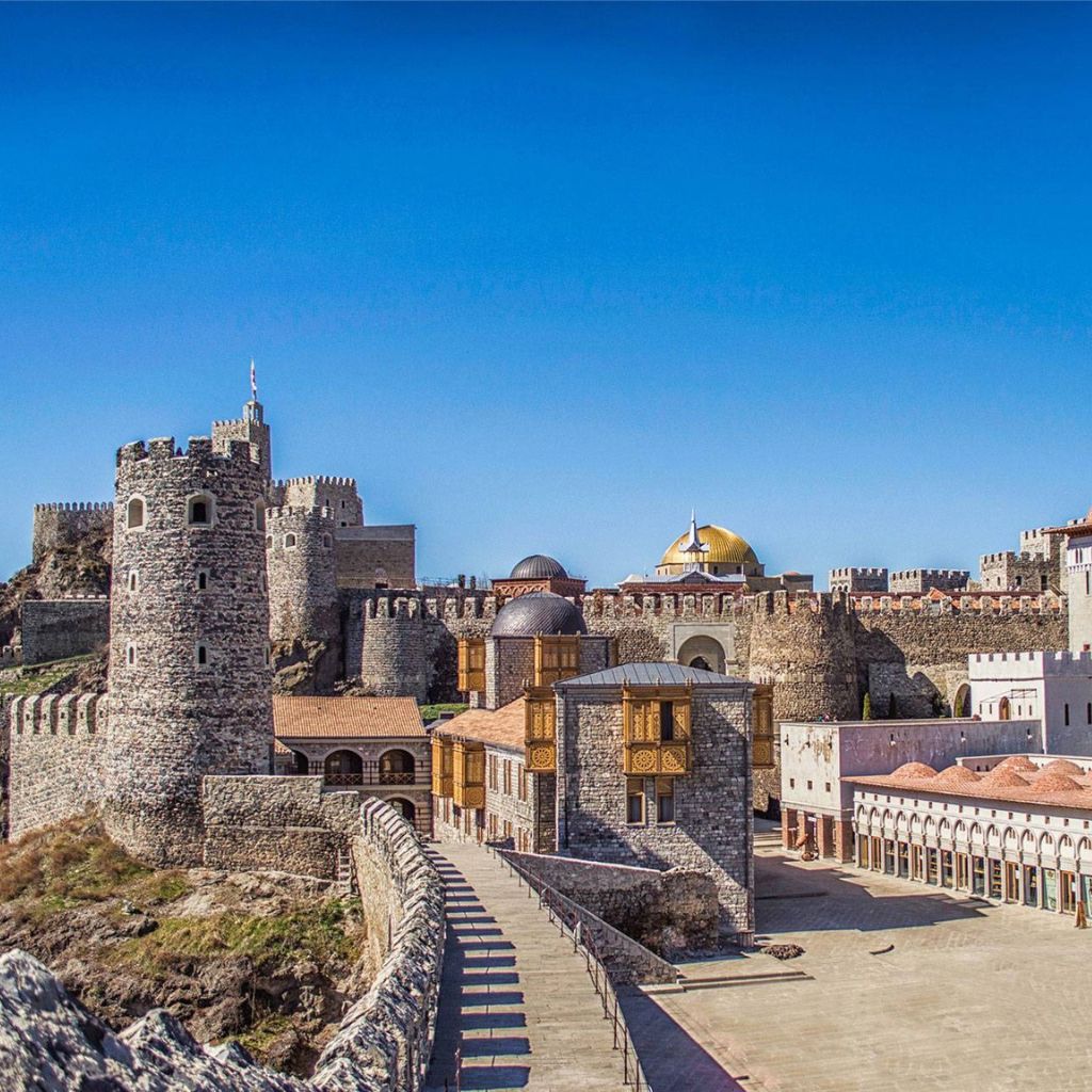 Akhaltsikhe Georgia , Ancient stone fortress under a clear blue sky, featuring towers, a golden dome, and detailed architecture. The scene conveys a sense of history.