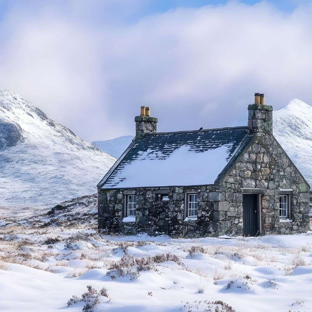 House in the Scottish Highlands surrounded by snow and mountain